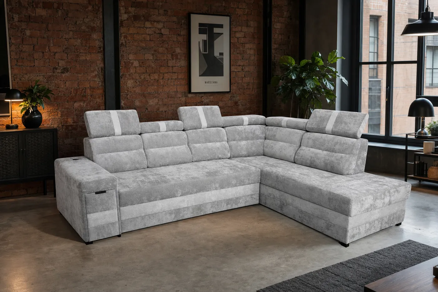 Szara sofa narożna w lofcie z ceglaną ścianą i plakatem Warszawy